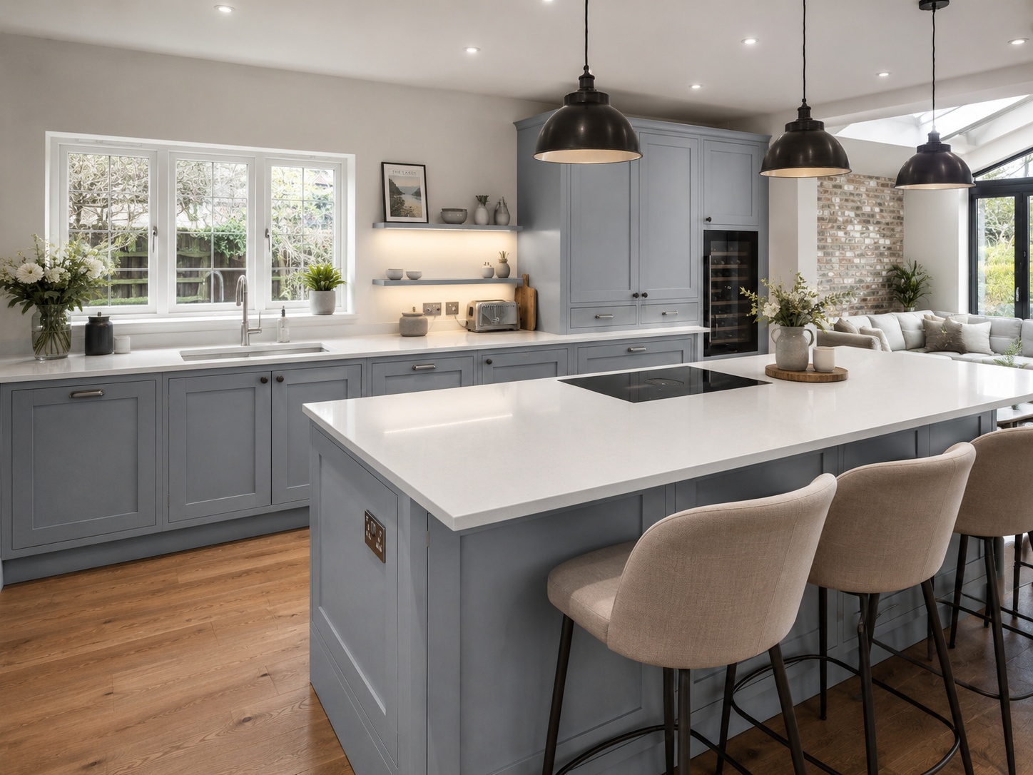 Nobilia Frame Stone Blue kitchen with shaker-style wood-textured doors, Alpine white compact worktop with crisp pale surface, warm wood flooring, integrated appliances and natural daylight in a UK kitchen-diner.