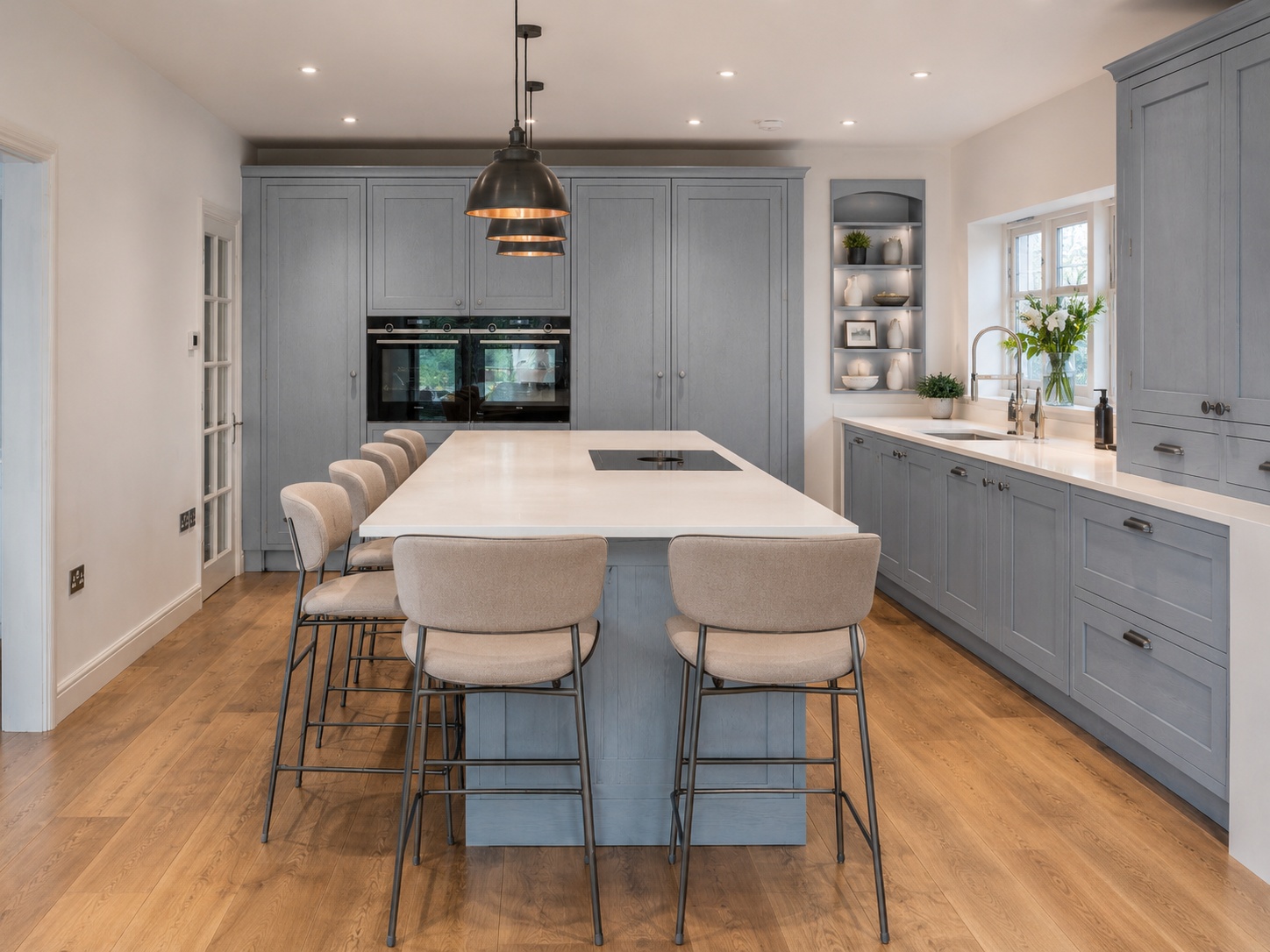 Nobilia Frame Stone Blue kitchen showing shaker-style wood-textured cabinet doors, Alpine white compact worktop with crisp pale surface, sink area, integrated appliances and warm natural daylight.