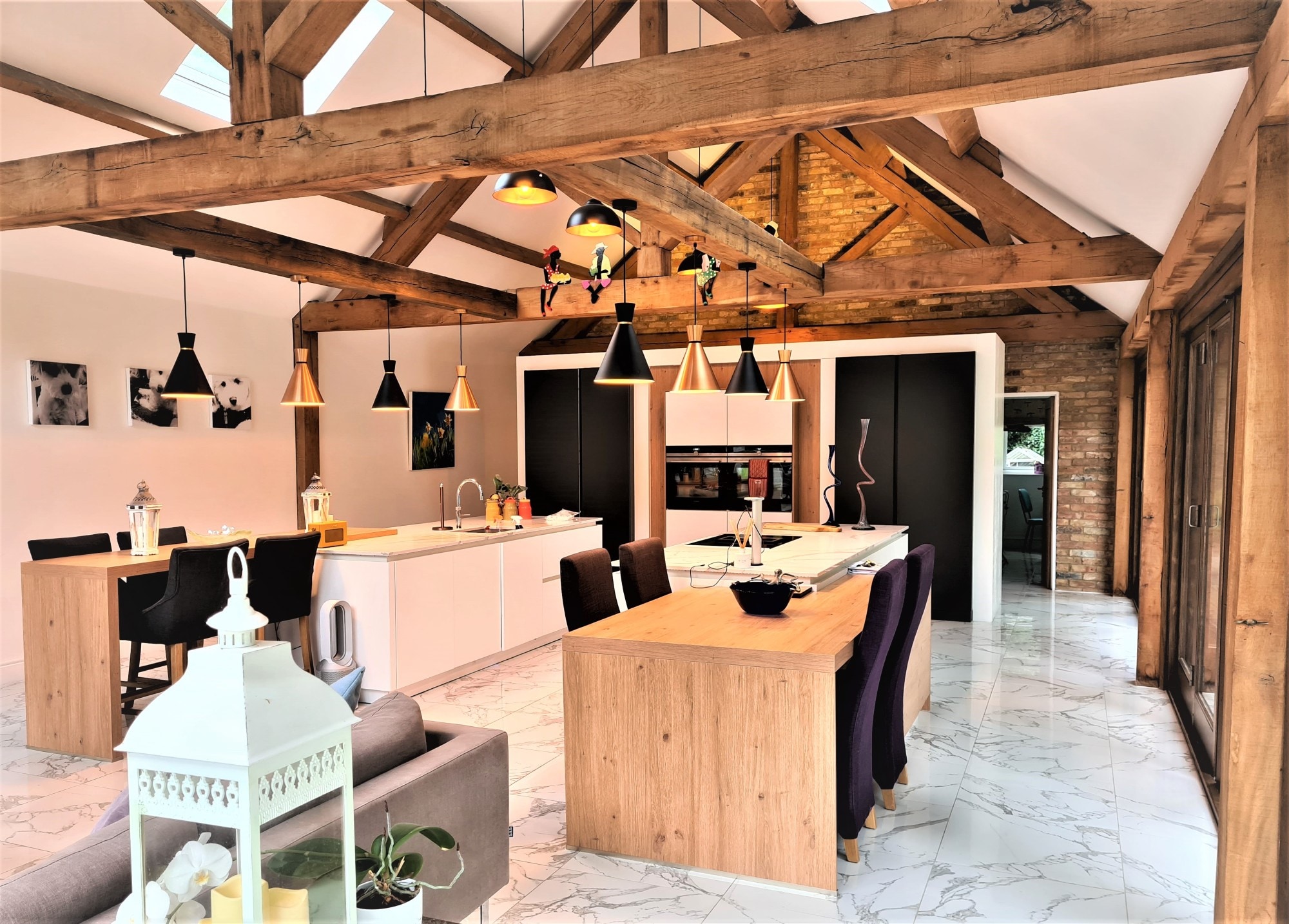 Open-plan kitchen and dining area with exposed wood beams and a white handleless island | Joshua Donald Kitchens, Dunstable